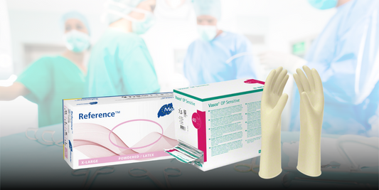 Zwei Schachteln mit Latexhandschuhen, eine mit der Aufschrift „Reference Powdered Latex“ und die andere mit „Vasco OP Sensitive“, stehen mit einem Paar Handschuhen aufrecht. Im Hintergrund ist eine verschwommene Ansicht von medizinischem Personal in OP-Kleidung und mit chirurgischen Masken in einem Operationssaal zu sehen.