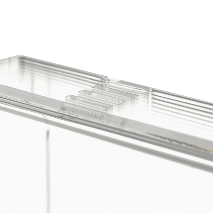 Közelkép az AMPri Handelsgesellschaft mbH átlátszó, tejszerű egyszer használatos kesztyű adagolójáról (250 x 135 x 55-90 mm), egy téglalap alakú akril adagolótartóról, bordázott élekkel, egyszínű fehér alapon.