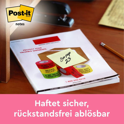 Egy sárga Post-it® Note, 76x76 mm, 100 lap/tömb (2 tömb/csomag), a 3M Deutschland GmbH-tól, "Lásd a 23. oldalt" felirattal egy íróasztalon. Alatta németül: "Biztonságosan tapad, maradvány nélkül eltávolítható.