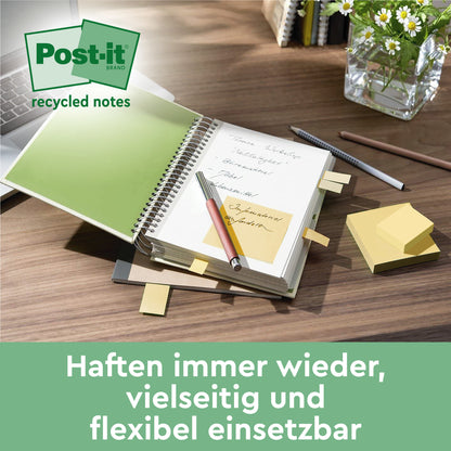 Ein Schreibtisch mit einem aufgeschlagenen Notizbuch mit 3M Post-it® Recycling Notes (76x76 mm, 100 Blatt/Block, 100% PEFC), einem Stift, zusätzlichen Blöcken, einem Wasserglas und einer Pflanze. Text: "Haften immer wieder, vielseitig und flexibel einsetzbar.