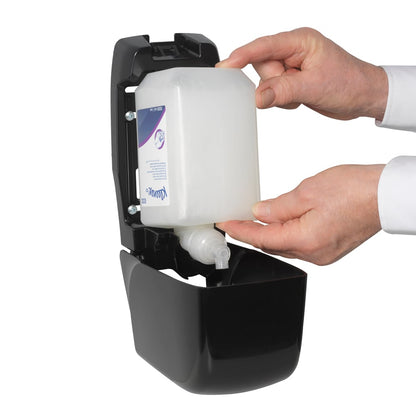 Egy személy behelyez egy Kleenex® haj- és testápoló sampon 1L-es kazettát a Kimberly-Clark GmbH-tól egy nyitott fekete falra szerelhető adagolóba, mindkét kezét használva a gyengéd ápolás és hatékony tisztítás biztosítása érdekében.