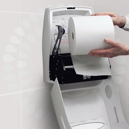 Egy személy egy Kleenex® Ultra™ kéztörlő - tekercset a Kimberly-Clark GmbH-tól egy fehér, nyitott falra szerelhető adagolóba helyez el egy mosdóban, hogy biztosítsa a higiénikus kézszárítást. Az adagoló fedelén egy útmutató van nyomtatva.