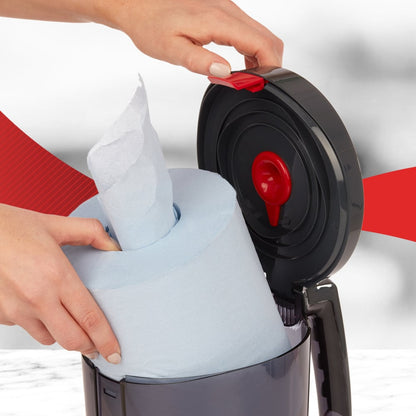 Egy felhasználó egy nagy kék tekercset helyez a nyitott WypAll® Reach™ Centrefeed adagolóba (fekete) a Kimberly-Clark GmbH-tól, amely a piros kioldó mechanizmust mutatja - tökéletes professzionális használatra.