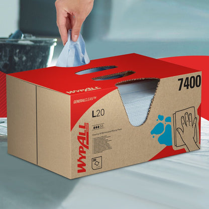 Egy kéz húz ki egy WypAll® L20 General Clean törlőkendőt egy kék BRAG™ dobozból a Kimberly-Clark GmbH-tól, amely 280 lapot tartalmaz, és egy sima felületre helyezi.