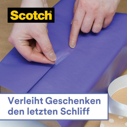 Egy személy kék csomagolópapírt zár le a Scotch® ajándék ragasztószalag kézi adagolóban, CAT 15 (19 mm x 15 m) a 3M Deutschland GmbH-tól. További ragasztószalag és az adagoló mellette fekszik. Német szöveg: "Végső simítást ad az ajándékoknak."
