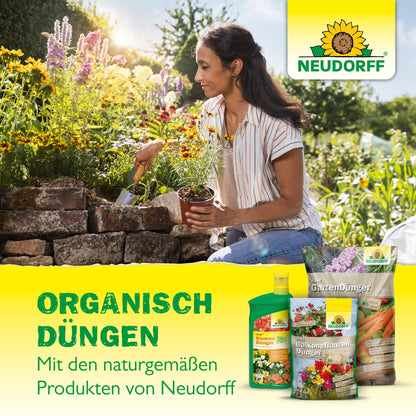 Egy nő egy kőből készült kerti ágyásnál guggol és hortenziákat ültet. Az előtérben az Azet HortensienDünger folyékony és más Neudorff Shop termékek vannak kiállítva. A német szöveg ezzel az organikus trágyával történő organikus trágyázást reklámozza.