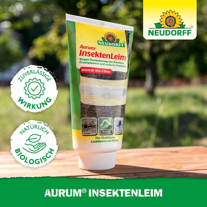 Egy tubus Neudorff Shop Aurum InsektenLeim áll egy kültéri asztalon. A csomagolás kiemeli a megbízható hatást a hangyák és téli molylepkék ellen, és természetes, biológiai összetevőkkel védi a gyümölcsfákat.