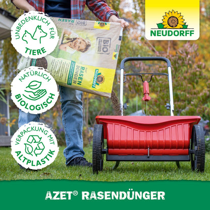 Egy személy piros szórót tölt meg Neudorff Shop Azet gyeptrágyával 2,5-5 kg, hogy elősegítse a sűrű gyepszőnyeget. Három szimbólum jelzi, hogy állatbarát, biológiailag természetes és újrahasznosított műanyagból készült. A Neudorff logó látható.