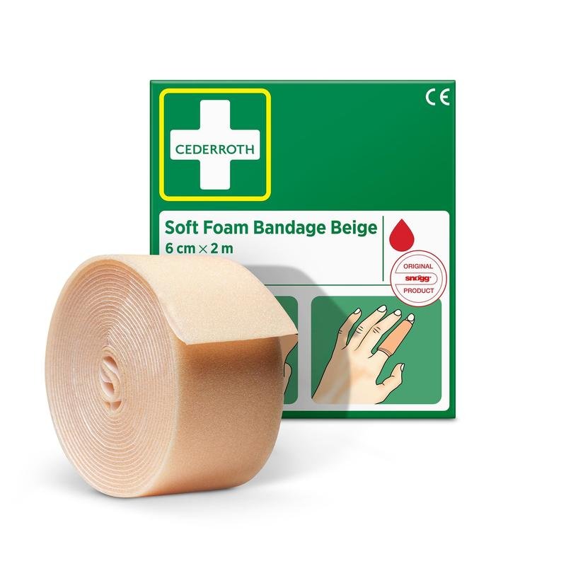 Egy bézs színű Cederroth puha habkötés (6 cm x 2 m) tekercs az Orkla Wound Care AB-től, zöld-fehér csomagolása előtt látható, illusztrált útmutatóval és egy piros cseppszimbólummal.