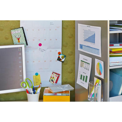Egy munkaterület egy falinaptárral, a 3M Scotch-FIX™ Eltávolítható Rögzítő Négyzetek 108-ST64-P-vel rögzített táblázatokkal, egy számítógép monitorral, színes mappákkal, egy ollóval egy fehér tartóban, egy sárga dobozzal és egy tollakkal teli pohárral. Jegyzetek ezekkel a maradványmentes ragasztópadokkal vannak rögzítve.
