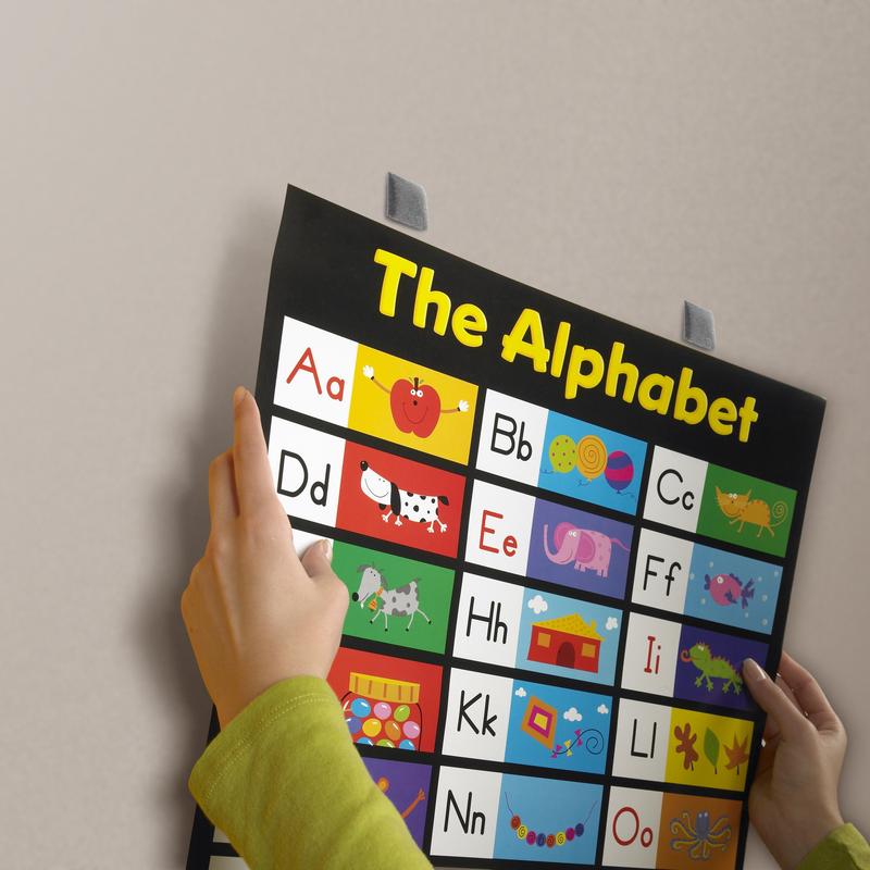 Egy személy egy élénk ábécétáblát mutat képes betűkkel, amelyet a 3M Deutschland GmbH Scotch-FIX™ Eltávolítható Rögzítő Négyzetek 108-ST64-P, 12,7 mm x 12,7 mm, ideiglenesen sima falra rögzítettek és könnyen eltávolíthatók. A csomag 64 darabot tartalmaz.