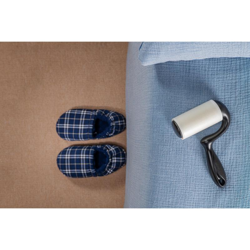 Egy pár kék kockás papucs áll egy bézs szőnyegen, egy világoskék takaróval borított ágy mellett, miközben a 3M Deutschland GmbH Scotch-Brite™ Everyday Clean szöszeltávolító lapos felületekre (56 lap, 1/csomag) az ágyon fekszik és használatra kész.