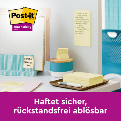 Egy halom Post-it® Super Sticky Notes, sárga, 76 mm x 127 mm, a 3M Deutschland GmbH-tól, néhány jegyzettel egy fehér falon egy rendezett irodában. A szöveg így szól: "Biztonságosan tapad, maradvány nélkül eltávolítható." 100% PEFC tanúsítvánnyal.