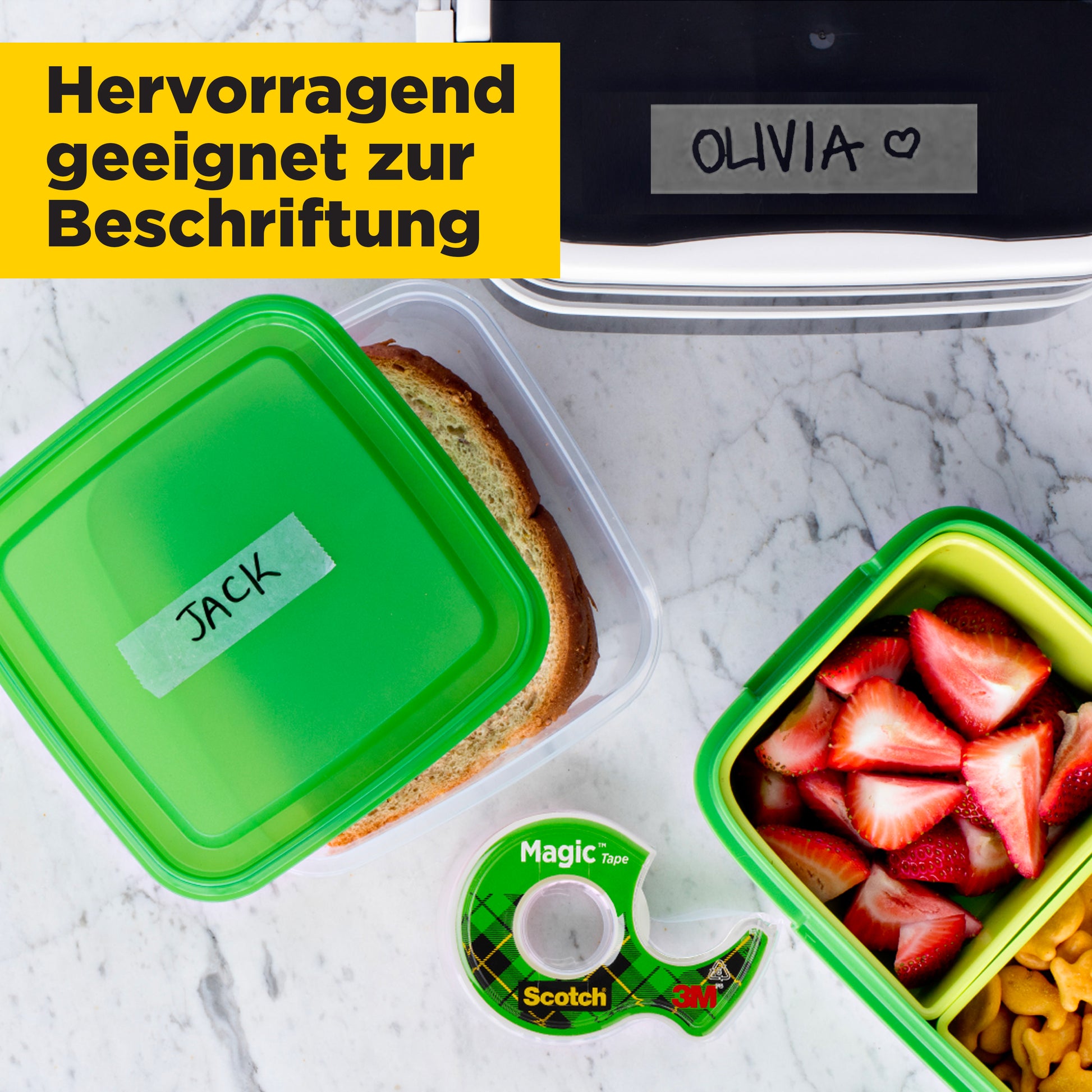 Zwei Brotdosen sind mit Scotch® Magic™ Unsichtbares Klebeband von 3M Deutschland GmbH beschriftet: "JACK" und "OLVIA ♥". Die Dosen enthalten ein Sandwich und Obst. Im Bild ist auch eine Packung mit Abroller zu sehen.