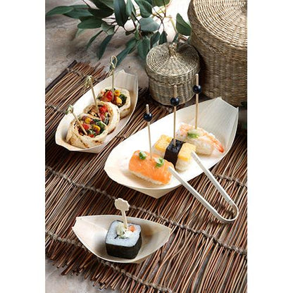 Fingerfood, mint a sushi és wrap nyársakon, PAPSTAR 50 fa fingerfood tálkában „pure” csónak formában a PAPSTAR GmbH-tól, bambusz szőnyegen, kosarakkal és zöld levelekkel a háttérben tálalva.