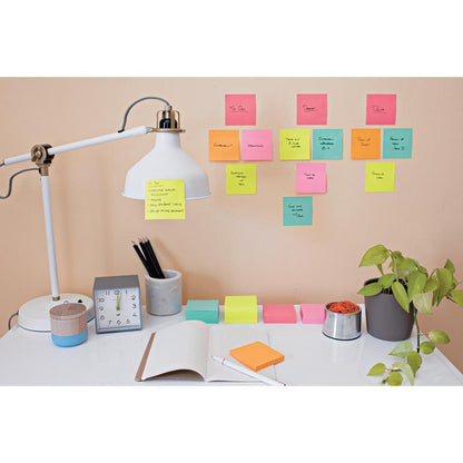 Egy íróasztal fehér lámpával, ceruzákkal egy csészében, egy órával, egy nyitott jegyzetfüzettel és egy növénnyel. A Post-it® Super Sticky Notes (47,6 mm x 47,6 mm) a 3M-tól kézzel írt feladatokkal a bézs falon az íróasztal felett van elrendezve.