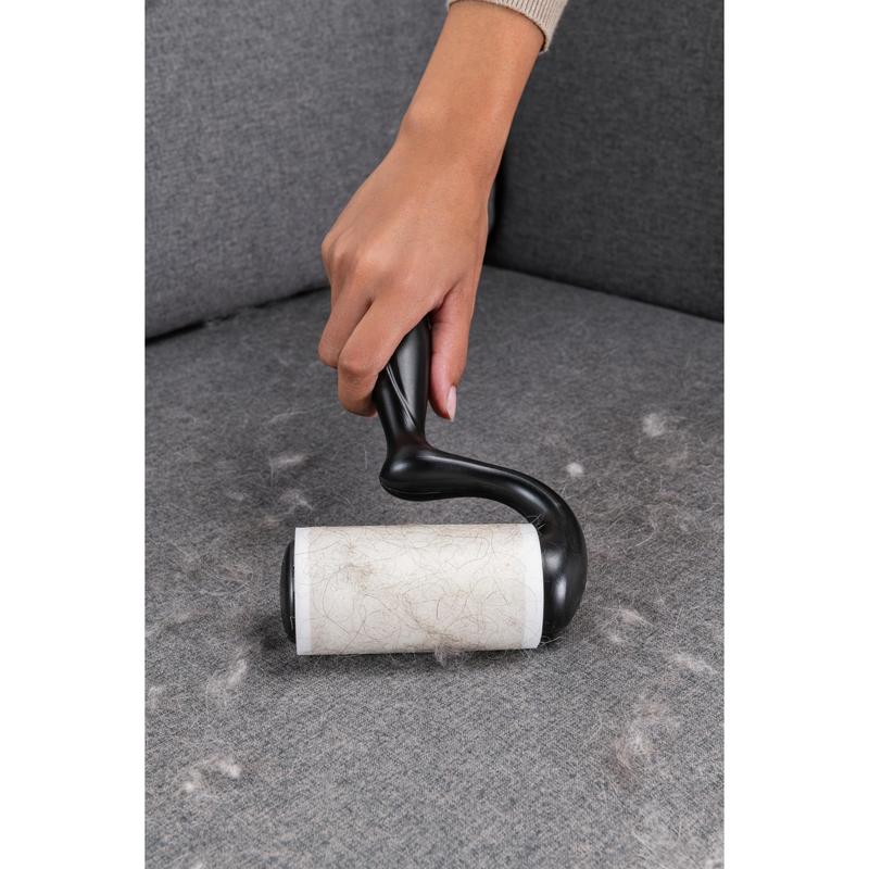 Egy kéz a Scotch-Brite™ Everyday Clean szöszeltávolító lapos felületekre, 56 lap (3M Deutschland GmbH) termékkel állatszőrt távolít el egy szürke kanapéról, hogy a felületek tiszták maradjanak.