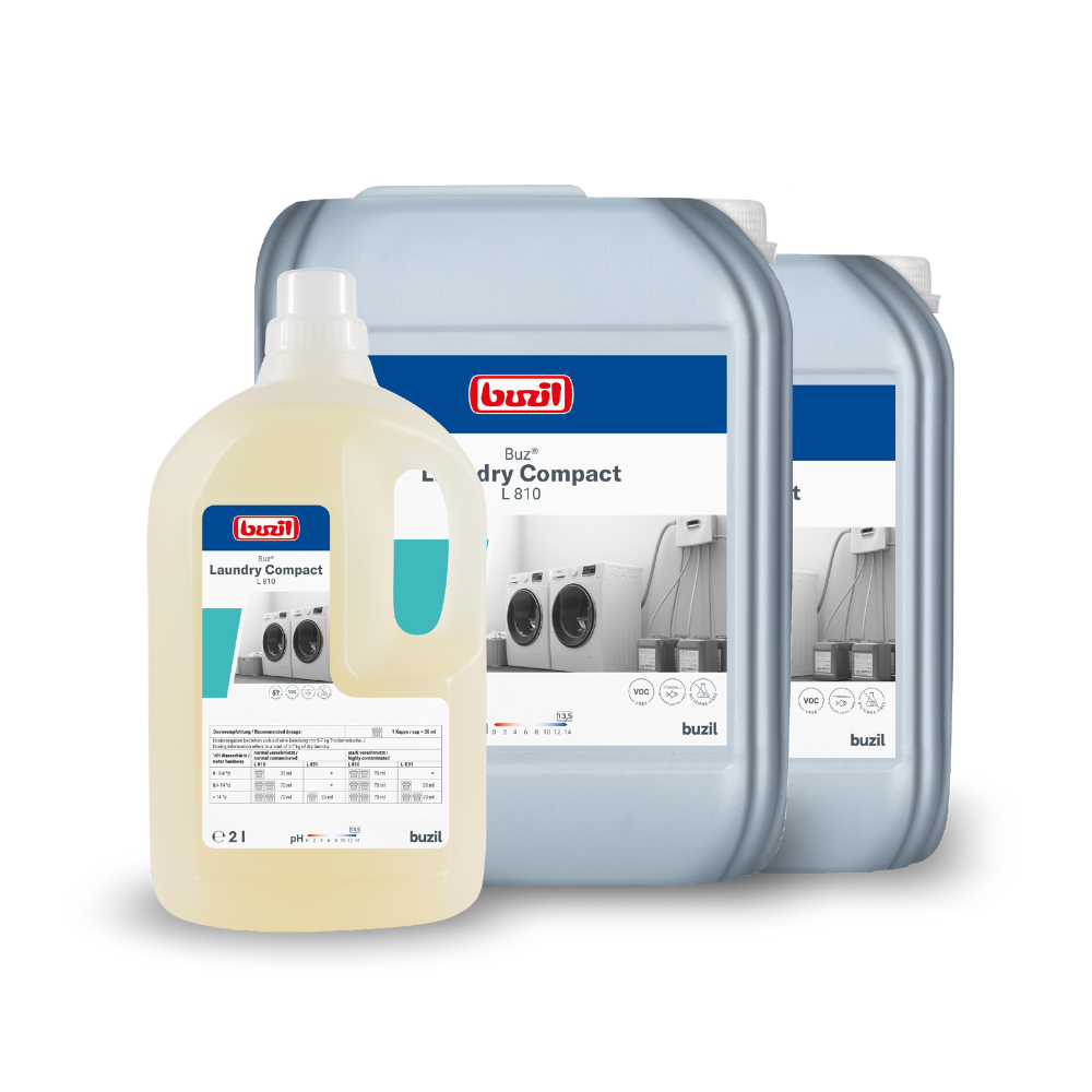 Ausgestellt sind drei Gebinde mit Buzil Buz® Laundry Compact L 810 Hochkonzentriertes Flüssigwaschmittel der BUZIL-WERK Wagner GmbH & Co. KG. Vorne eine kleinere, klare Flasche, dahinter zwei größere, graue Gebinde. Auf jedem Gebinde sind Etiketten mit Texten und Bildern von Waschmaschinen angebracht, die auf die Funktion des Waschmittels in der professionellen Textilpflege hinweisen.