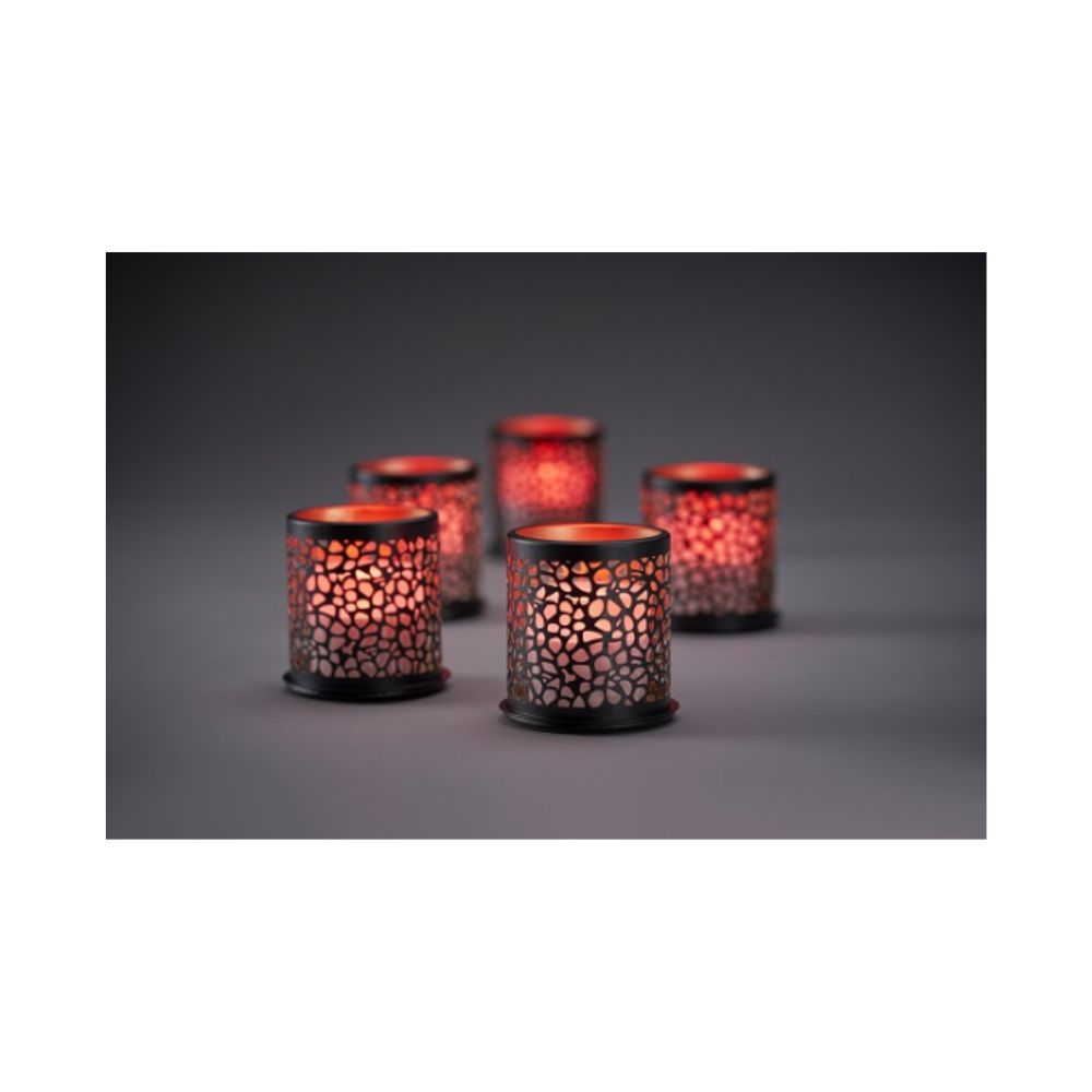 Acht leuchtende Multicolour LED Set, Mini-Kerzen der Duni GmbH in gemusterten Haltern werfen ein warmes, farbenfrohes Licht durch perforierte Muster auf eine dunkle Oberfläche; der sanft verschwommene Hintergrund verstärkt die gemütliche Stimmung.