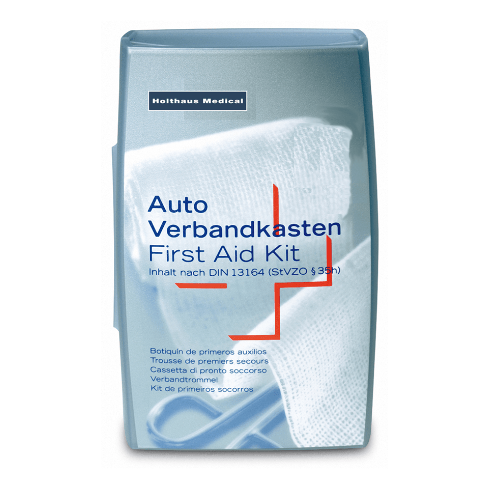 Egy ezüstös Holthaus ezüst elsősegély-készlet a Holthaus Medical GmbH & Co. KG-től. A borítón található szöveg többnyelvű, és az „Autós elsősegélycsomag / Elsősegélydoboz” felirat szerepel rajta, valamint jelzi, hogy megfelel a DIN 13164 (StVZO §35h) szabványnak. A háttérben egy fehér orvosi kötés látható, ideális orvosi vészhelyzetekhez.