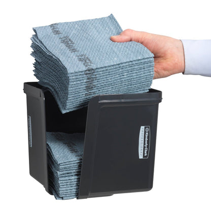 Egy kéz negyedbehajtott törlőkendőket helyez el a szürke Kimberly-Clark Professional™ törlőkendő-adagolóba a Kimberly-Clark GmbH-tól - a higiénikus kendőkivétel érdekében. A szépen hajtogatott kendők és az elülső címke láthatóak.