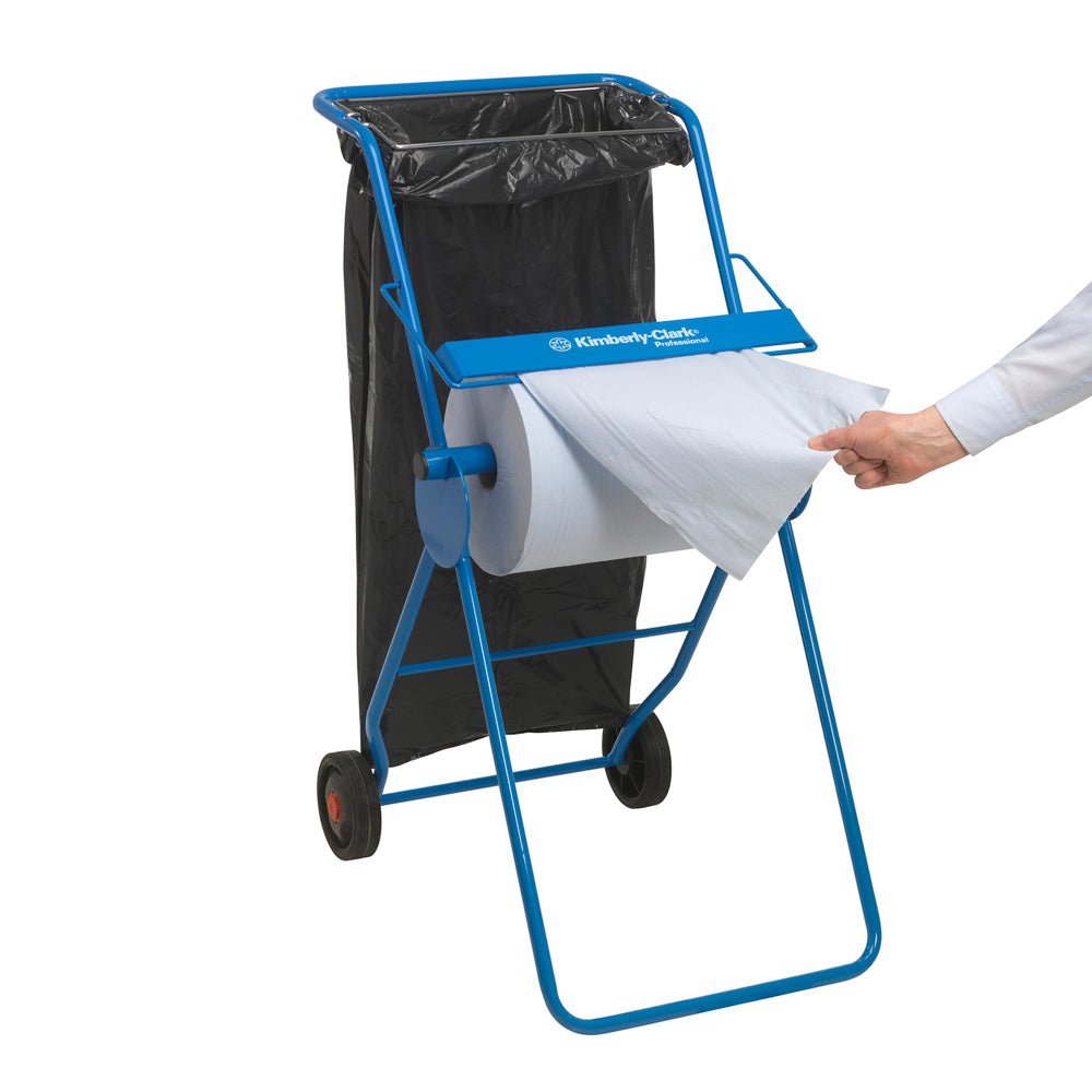 Egy kék papírtörlő adagoló fekete szemeteszsákkal látható, miközben egy kéz egy lapot húz ki a WypAll® X60 General Clean nagy tekercsből (1 tekercs x 500 lap, kék) a Kimberly-Clark GmbH-tól - ideális professzionális tisztítási feladatokhoz.
