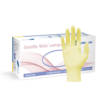 Kiállítva van egy doboz közepes méretű, púdermentes orvosi kesztyű, Meditrade Gentle Skin® Latexhandschuhe compact+ egyszer használatos kesztyű, előtte pedig egy sárga latex egyszer használatos kesztyű van kinyújtva.