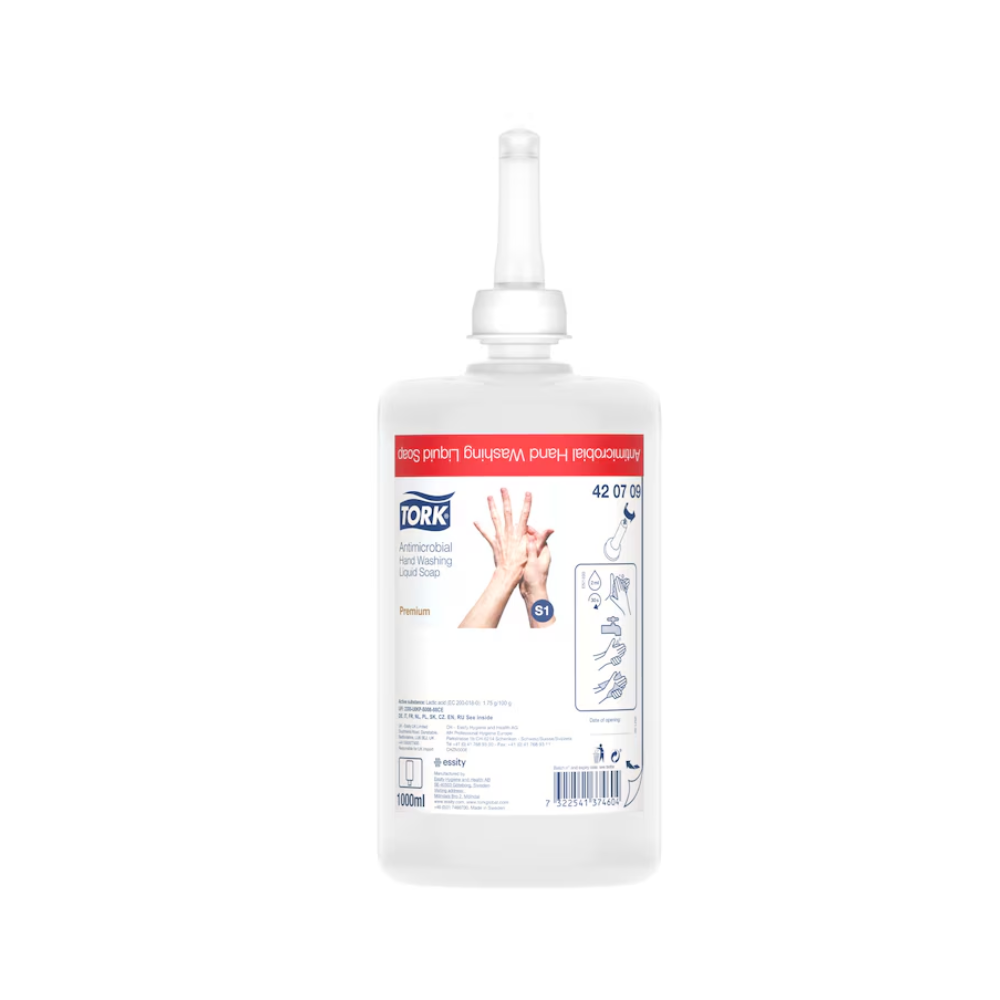 A képen egy Tork folyékony szappan látható kézfertőtlenítéshez, adagoló utántöltő palack egy fúvókával. A címke használati utasításokat, a TORK márkanevet – Essity Professional Hygiene Germany GmbH és termékrészleteket mutat. Az átlátszó palack betekintést nyújt a belső folyadékra, így hangsúlyozva az élelmiszer-feldolgozásban való használatát. A címke főként piros és fehér színekben van tartva.