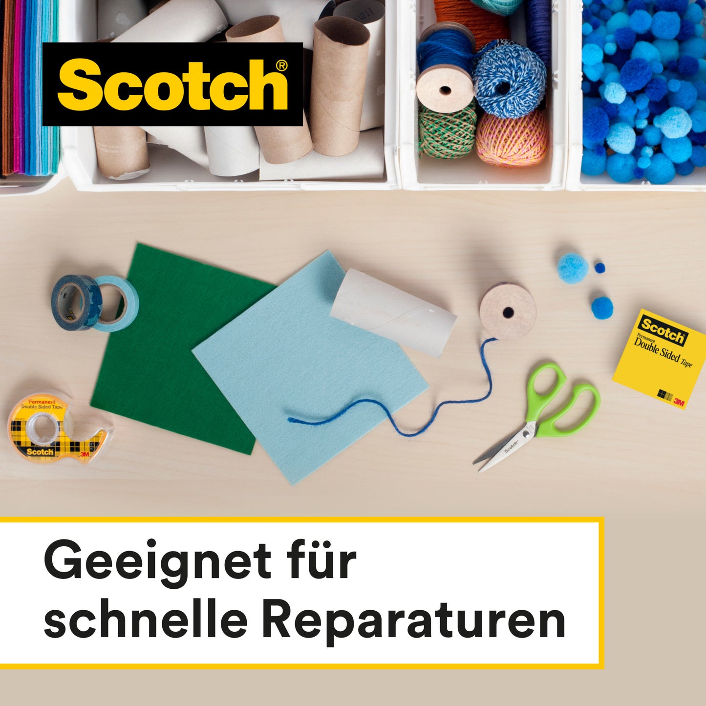 Auf einem Tisch mit Bastelmaterial - Schere, farbiges Papier, Schnur, Pappröhre und Bommeln - liegt das Scotch® doppelseitige Klebeband (Nachfüllpackung, 2 Rollen, 12 mm x 6,3 m) der 3M Deutschland GmbH für schnelle Reparaturen.