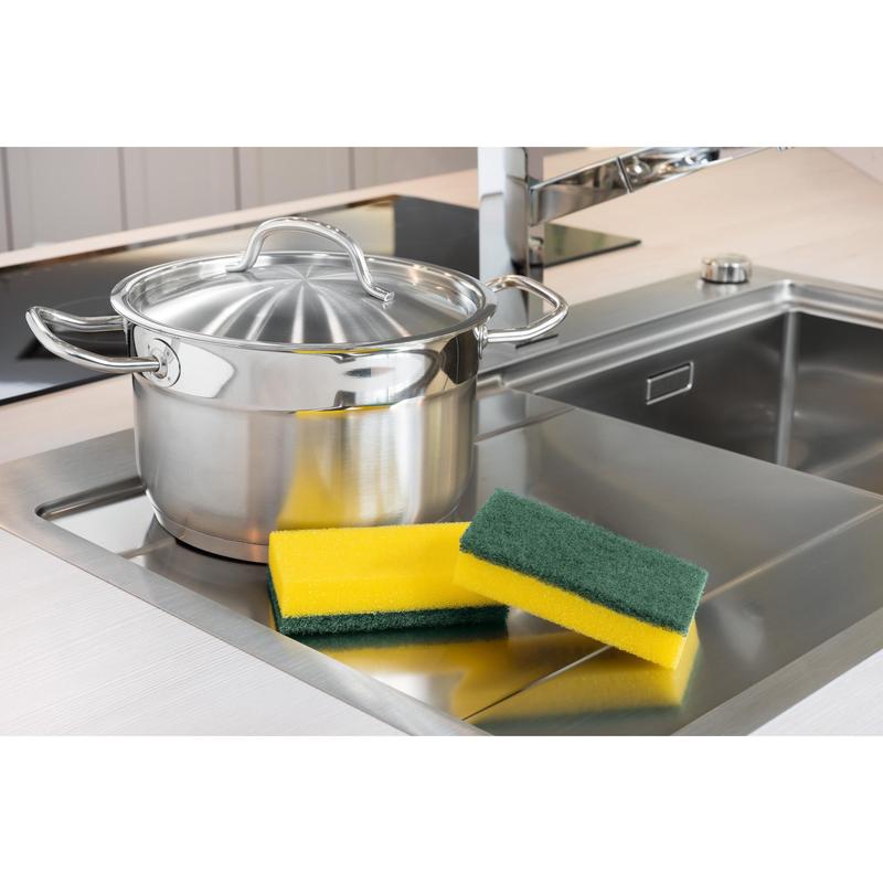 Egy rozsdamentes acél edény fedéllel áll a mosogató mellett. Mellette három szivacs található, köztük egy 3M Deutschland GmbH Scotch-Brite® Classic XXL tisztítószivacs (6 darab csomagonként). A háttérben egy modern vízcsap látható.