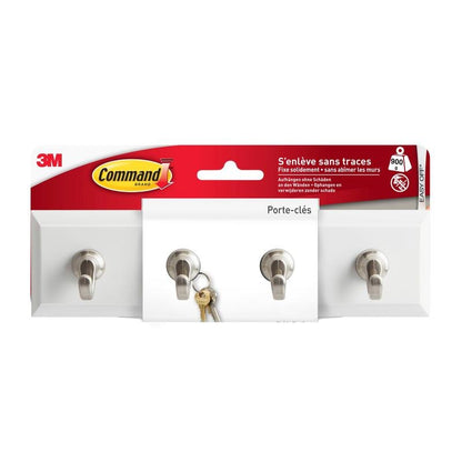 A Command™ kulcstartó sín kvarc színben, HOM18-Q a 3M Deutschland GmbH-tól három fém akasztóval van bemutatva a kulcsok tárolására. A kulcsok a középső akasztón lógnak, és a francia címke az egyszerű és gyors telepítést hangsúlyozza.