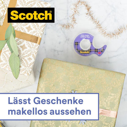 A Scotch® ajándék ragasztószalag kézi adagolóban CAT 15 (19 mm x 15 m) a 3M Deutschland GmbH-tól világos háttéren fekszik két szépen becsomagolt ajándék mellett aranyszalaggal és ággal. Szöveg: "Makulátlan megjelenést kölcsönöz az ajándékoknak."