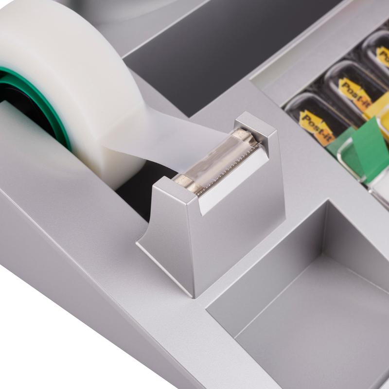 Közelkép a 3M Deutschland GmbH Post-it® asztali rendezőjéről, amely Post-it® jegyzetlapokat, indexeket és Scotch® Magic™ ragasztószalagot (1 darab) tartalmaz, bemutatva a fogazott élű ragasztószalag-adagolót és a szomszédos asztali rendező rekeszeket.