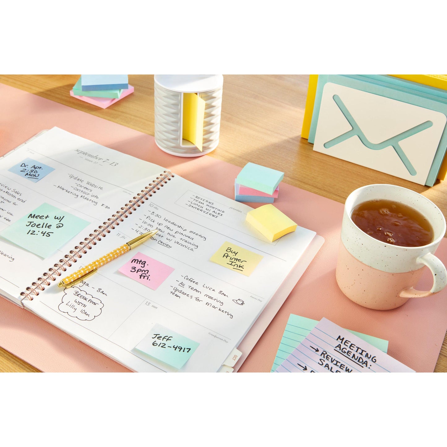 Egy íróasztalon található egy tervező Post-it® Recycling Z-Notes-szal (sárga, 76x76mm, 100% PEFC) a 3M Deutschland GmbH-tól, egy ceruza, egy teáscsésze, egy halom indexkártya, egy kis tárolódoboz és egy boríték alakú tartó.