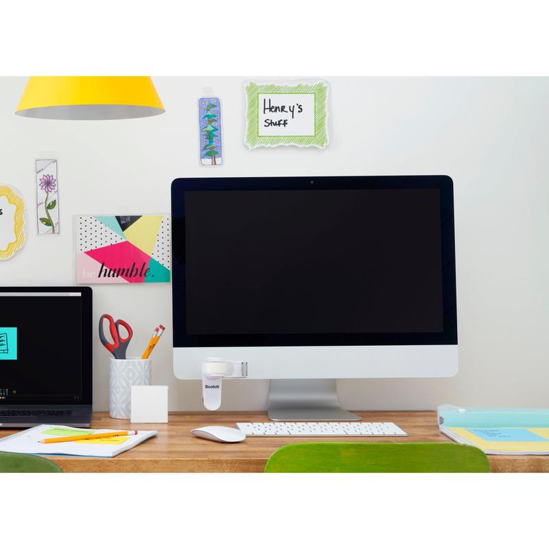 Egy rendezett íróasztal nagy monitorral, zárt laptoppal, tollakat és ollókat tartalmazó bögrével, irodai eszközökkel és a 3M Scotch™ Clip & Twist ragasztószalag-adagoló C19 Magic™ Láthatatlan ragasztószalaggal a kijelzőn. A falon olyan dekoratív jegyzetek találhatók, mint "Henry's Stuff".