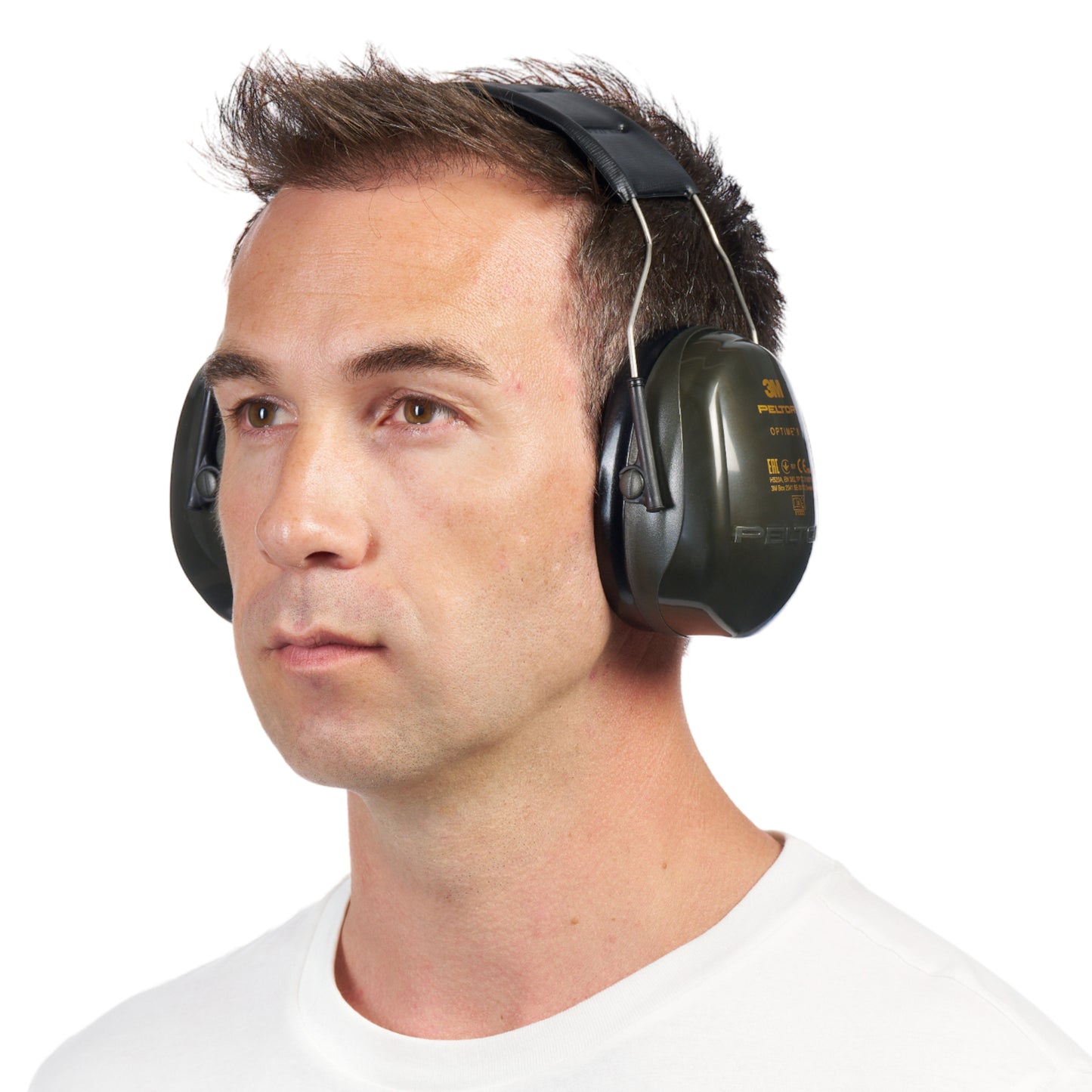 Ein Mann mit kurzen braunen Haaren, in einem schlichten weißen Hemd, trägt große grüne 3M™ PELTOR™ Optime™ II H520A Kapselgehörschützer (SNR 31 dB, 1 Stück) von 3M Deutschland GmbH, leicht nach links gewandt vor einem weißen Hintergrund.