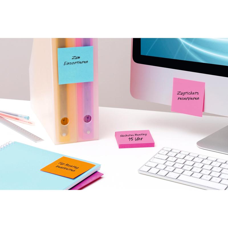 Egy íróasztali jelenet pasztell színű mappákkal, jegyzetfüzetekkel és sárga 3M Post-it® jegyzetlapokkal (76x76 mm, 90 lap/blokk, 6 blokk, 100% PEFC), amelyek irodai kellékekhez és monitorhoz vannak rögzítve, egy fehér billentyűzet és egy kék képernyő mellett.