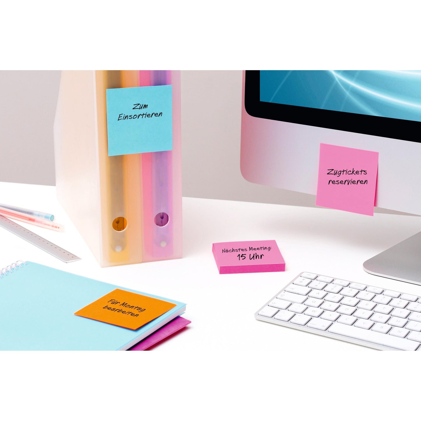 Az íróasztalon egy számítógép, egy billentyűzet, mappák, vonalzó, jegyzetfüzet és színes Post-it® Super Sticky Notes kocka (76 x 76 mm, 100% PEFC) található a 3M Deutschland GmbH-tól értekezlet-emlékeztetők és szervezés céljából.