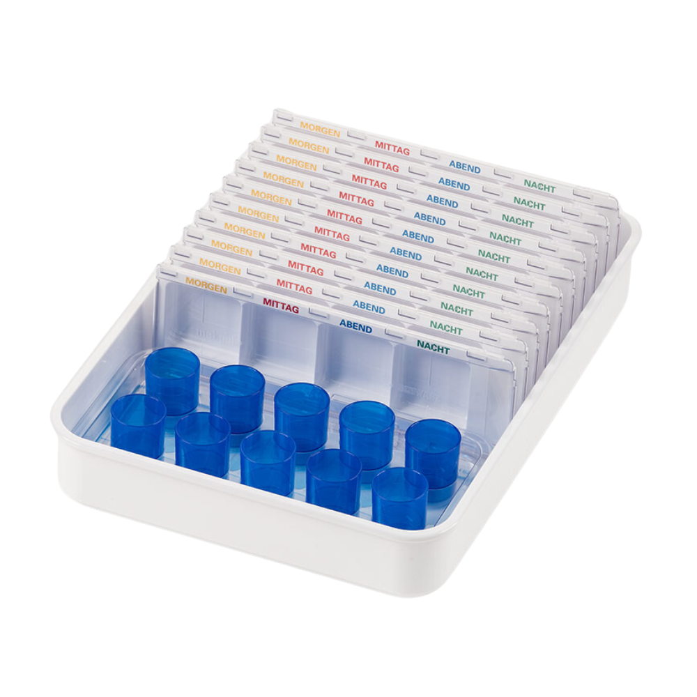 Egy fehér Melipul adagoló-/pohártálca a Helmut Schwarz GmbH-tól több átlátszó pirulaadagolót tartalmaz, amelyek egy gyógyszerszervezési rendszer részét képezik, német szavakkal feliratozva a napszakokra: „Reggel”, „Dél”, „Este”, „Éjszaka”. Minden újrafelhasználható adagoló nyílásokkal rendelkezik a pirulák számára és kék fedelekkel az egyik oldalon.