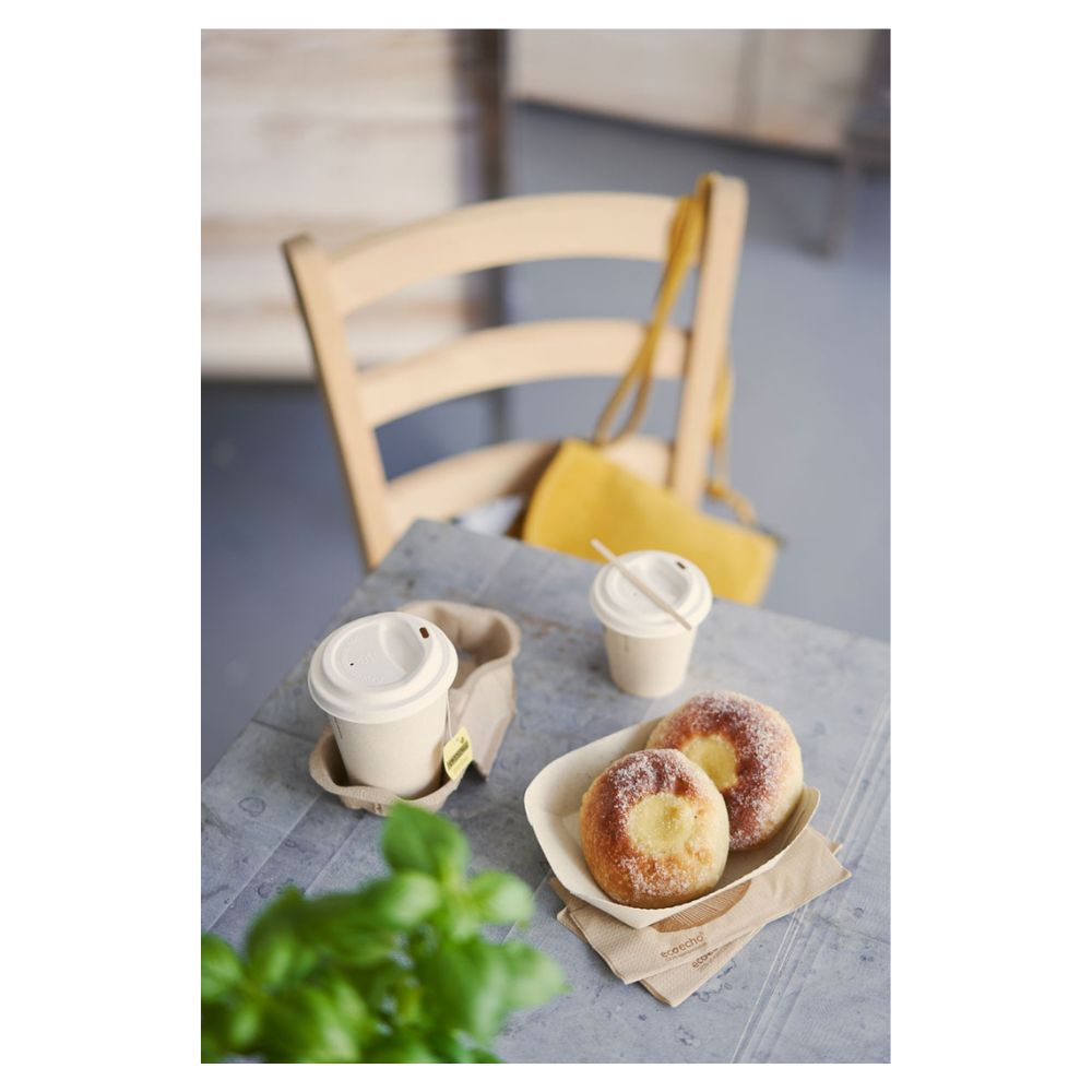 Egy asztalon két cukorral megszórt sütemény található egy tálcán, valamint két fedeles Duni-Kaffeebecher „Sweet Nyomtatott Bagasse” a Duni GmbH-tól. Egy sárga kézitáska lóg egy fa széken, míg egy részben látható zöld növény az előtérben finoman kiemeli a fenntarthatóság témáját.